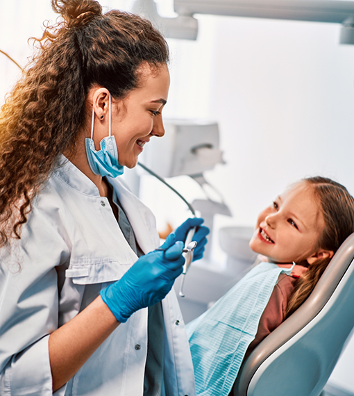 Young girl in dental chair grinning at her pediatric dentist in Portland