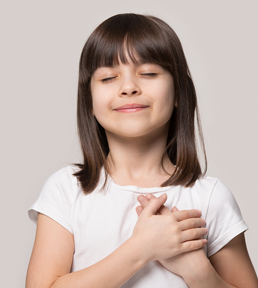 Smiling girl with her eyes closed and her hands over her heart