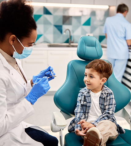 Toddler in dental chair looking at his dentist