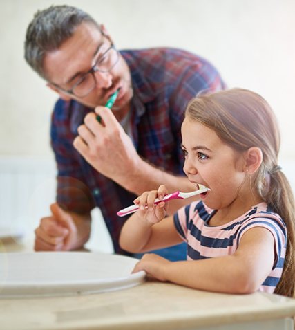 Man brushes teeth with daughter