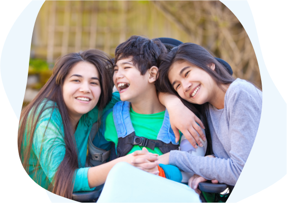 Two girls hugging a boy in a wheelchair