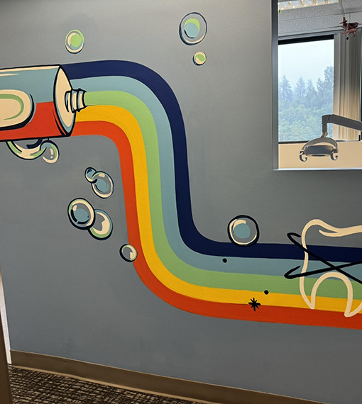 Painting of rainbow toothpaste on wall of pediatric dental office in Portland
