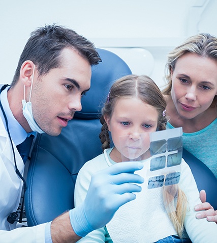 Dentist showing patient and mother X-rays of teeth