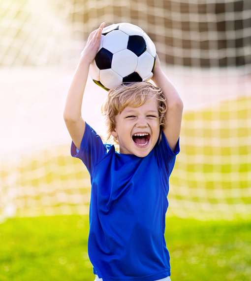 Child holding a soccer ball above their head