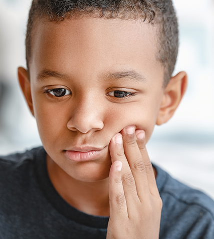 Boy holding his cheek in pain