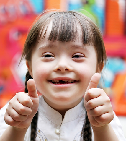 Smiling girl with Down syndrome giving two thumbs up