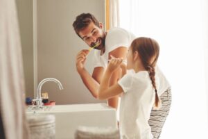 A father and daughter brushing their teeth together
